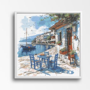 May include: A painting depicting a charming seaside village with a small sailboat in the harbour. A table with blue chairs sits on a cobbled street in front of a white building with a red door.