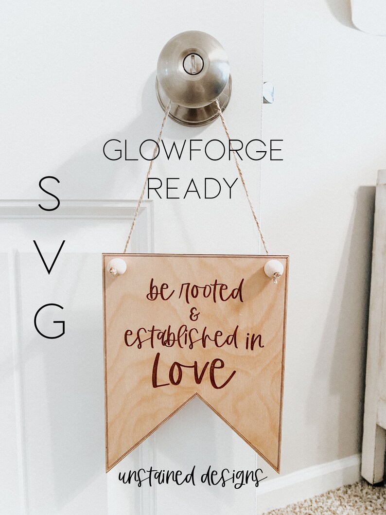 May include: A wooden banner sign with the text "be rooted & established in Love" in a dark brown script. The sign is suspended from a door knob with twine and small white decorative balls. The words "GLOWFORGE READY", "SVG", and "unstained designs" are also visible.