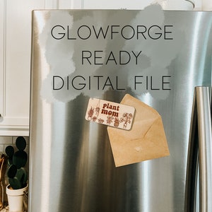 May include: A stainless steel refrigerator with the text "Glowforge Ready Digital File" written on it. A brown envelope with a wooden sign that says "Plant Mom" is attached to the refrigerator with a magnet.