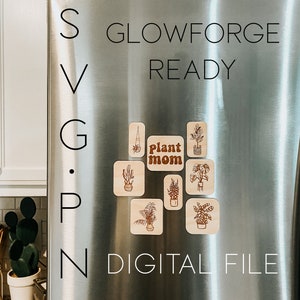 May include: A stainless steel refrigerator with the words "Glowforge Ready" and "SVG.PNG.DIGITAL FILE" written on it. There are several wooden plant-themed magnets on the refrigerator, including one that says "Plant Mom".