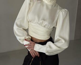 Blusa de satén de seda color marfil con espalda abierta, mangas largas y cuello alto para noche, fiestas y citas.