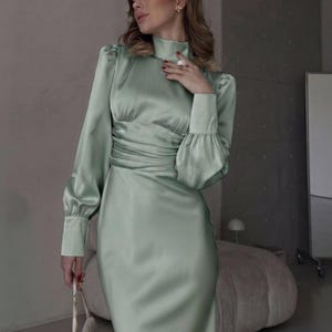 Front view of sage green satin midi dress showing the high mockneck, long fitted sleeves, and fitted bodice in smooth sage green satin