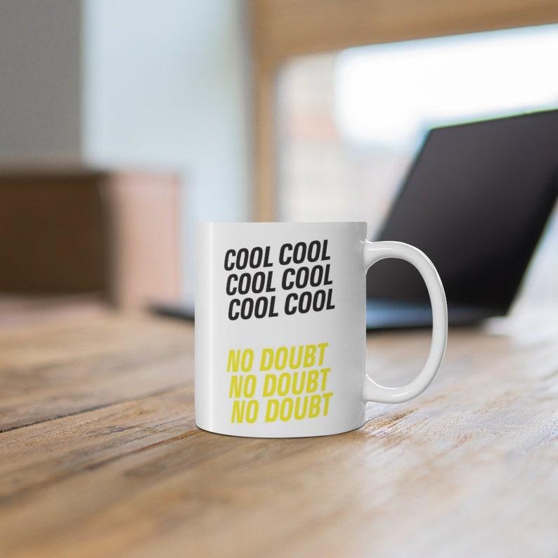 Peut inclure: Une tasse en c&eacute;ramique blanche avec du texte noir qui dit "Cool Cool Cool Cool No Doubt No Doubt No Doubt". Le texte est en jaune.