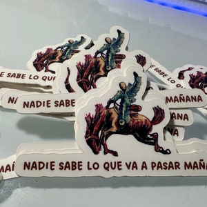 May include: A stack of white stickers with a brown illustration of a person riding a horse. The text on the stickers reads "Nadie sabe lo que va a pasar mañana" which translates to "Nobody knows what will happen tomorrow".