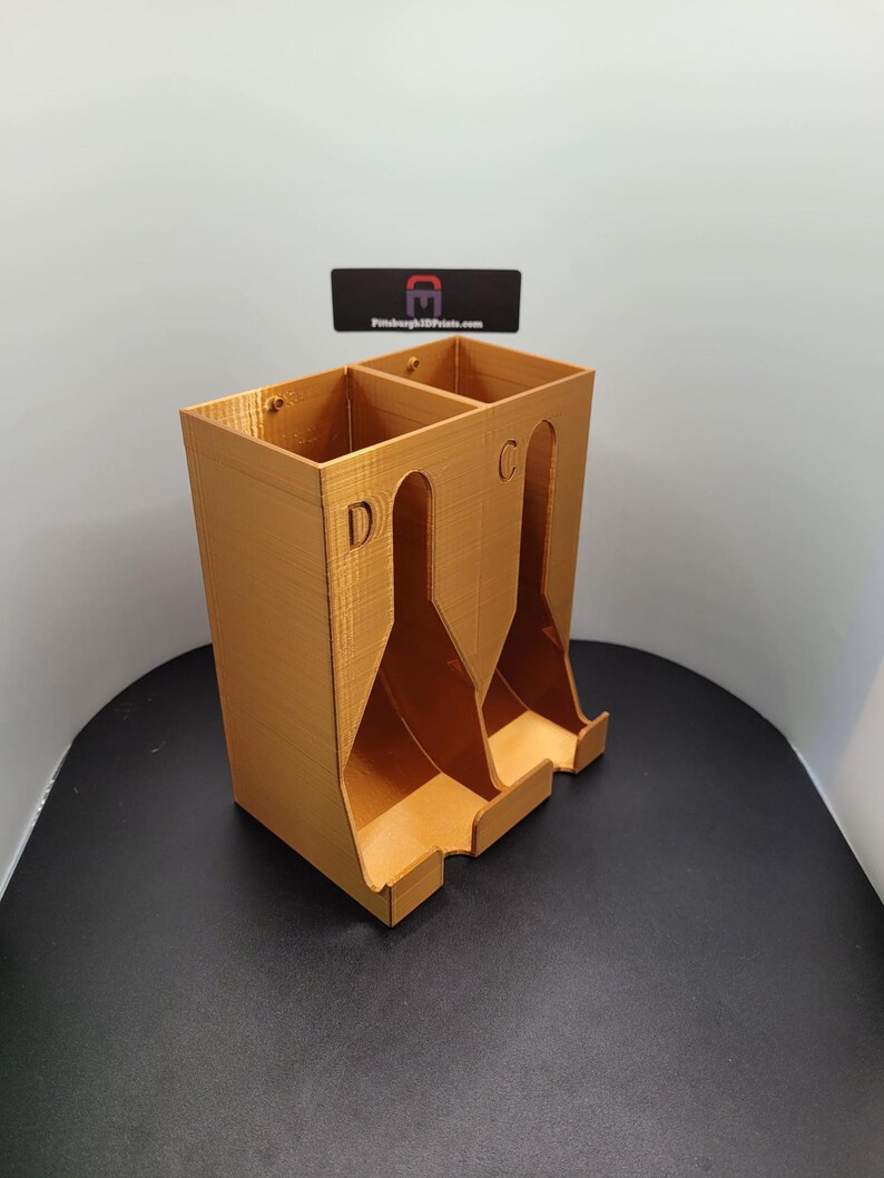 May include: A gold-colored 3D printed organizer with three compartments labeled "C", "D", and "E".
