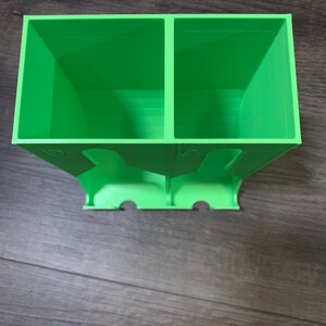May include: A green plastic organizer with two compartments. The organizer has a series of holes on the bottom.