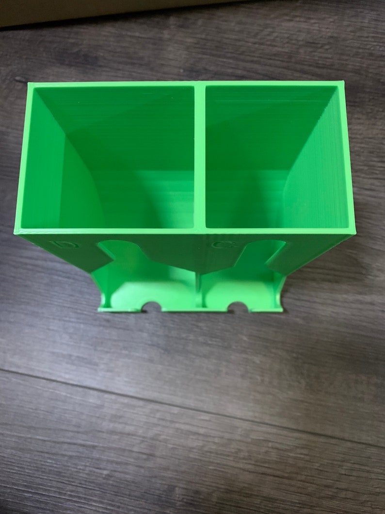 May include: A green plastic organizer with two compartments. The organizer has a series of holes on the bottom.