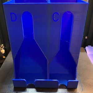 May include: A blue plastic organizer with two compartments labeled "C" and "D". The organizer has a rectangular shape and is designed to hold items upright.