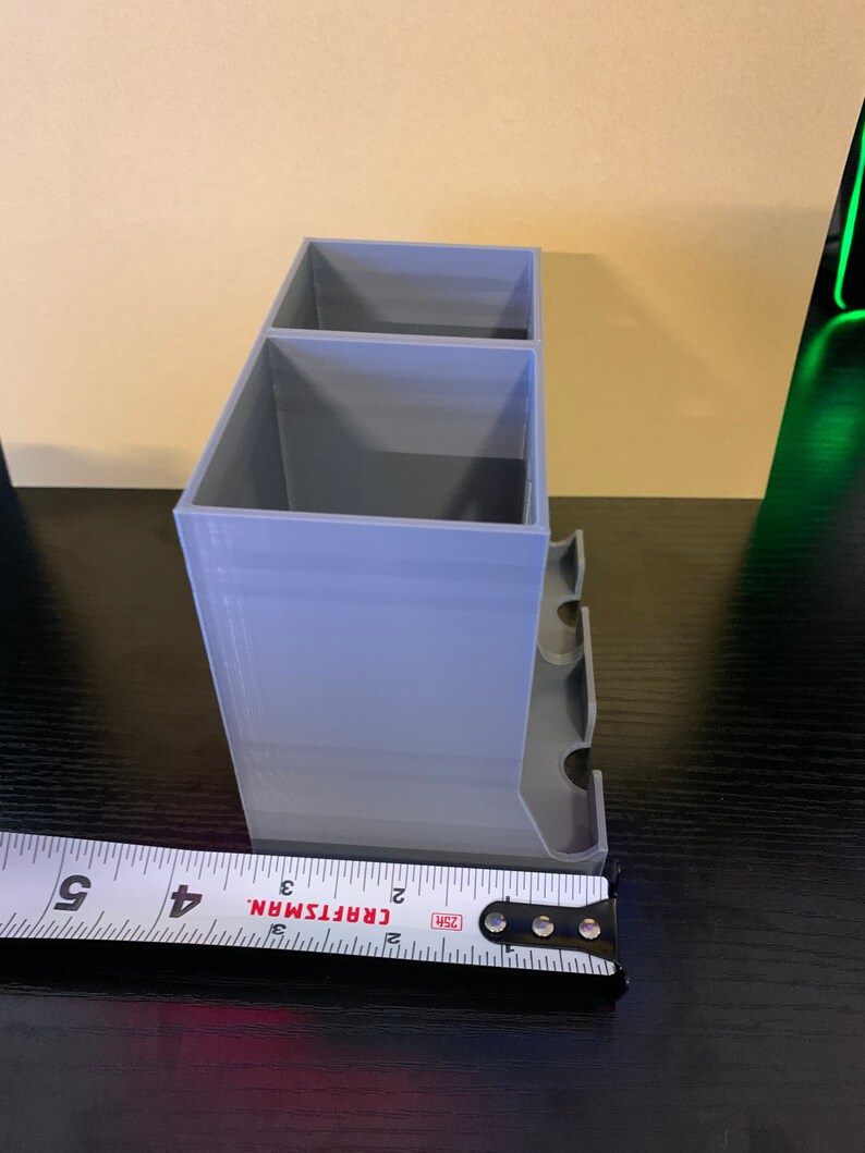 May include: A gray plastic organizer with two compartments and a side shelf. The organizer is 3 inches wide.