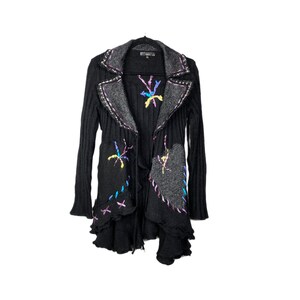 May include: Black knitted cardigan with a long, asymmetrical hemline and colorful embroidered details. The cardigan has a shawl collar and a tie closure.