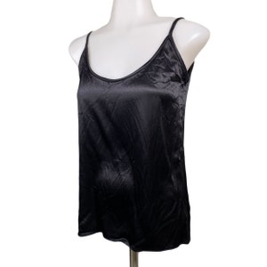 May include: A black satin tank top with thin straps. The top is sleeveless and has a scoop neck.
