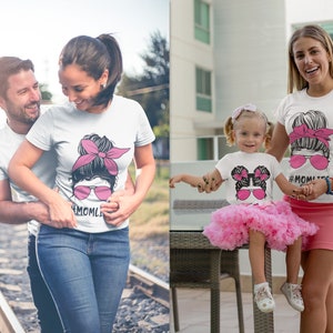 Peut inclure: T-shirts blancs avec un graphisme de visage f&eacute;minin portant des lunettes de soleil roses et un bandeau rose. Le texte "#MOMLIFE" est en dessous. L'image montre un couple et une m&egrave;re et sa fille portant les t-shirts.