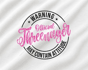 Könnte beinhalten: Eine weiße Stoffoberfläche mit einer kreisförmigen schwarzen Grafik, die den schwarzen Text WARNING, Official und MAY CONTAIN ATTITUDE enthält, um das Wort Threenager in einer großen, glitzernden, leuchtend pinken Schreibschrift.