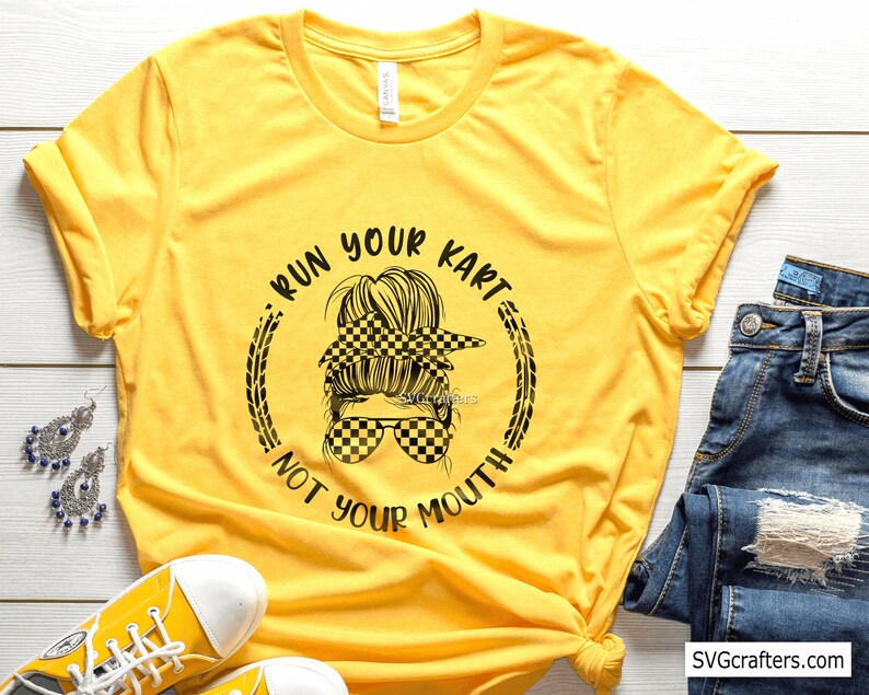 May include: Yellow t-shirt with a black and white checkered design of a woman with a messy bun and sunglasses. The text "Run Your Kart Not Your Mouth" is written around the design.
