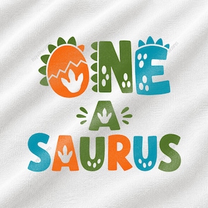 May include: A white fabric surface featuring a colorful graphic design with the text ONE A SAURUS. The letters are styled with dinosaur-themed elements, including spikes, spots, and footprints, in shades of orange, green, and blue.