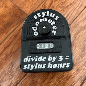 May include: Black stylus meter with a digital display reading "0120". The meter has a circular dial with the text "stylus meter" and the instruction "divide by 3 = stylus hours".