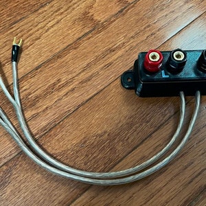 May include: A black speaker wire splitter with four gold-plated banana plugs. The splitter has two sets of left and right speaker terminals labeled "L" and "R".