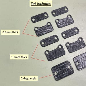 May include: A set of black, rectangular components with rounded corners and two holes each. Some pieces are 0.6mm thick, others 1.2mm thick, and some have a 5-degree angle. The text "Set Includes" is at the top.