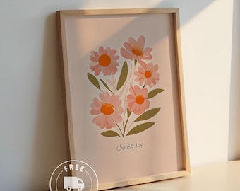 Op de afbeelding: Een ingelijste kunstdruk met een bloemenillustratie. Het kunstwerk toont roze bloemen met oranje centra en groene bladeren tegen een lichtroze achtergrond. De zin "Choose Joy" staat onderaan.
