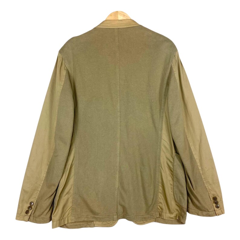 May include: Back view of a tan blazer with a two-button closure and three buttons on each sleeve. The blazer has a notched lapel and a tailored fit. The fabric appears to be a cotton blend.
