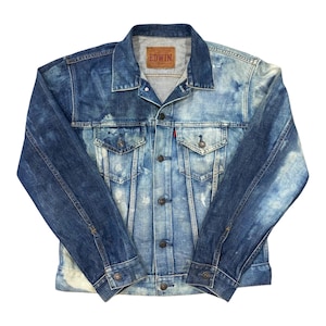 Può includere: Giacca di jeans blu slavata con effetto lavato. La giacca presenta un colletto classico, chiusura con bottoni e più tasche. Il marchio "EDWIN" è visibile su un'etichetta marrone. Un'etichetta rossa è sulla tasca.