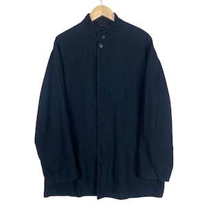 K&ouml;nnte beinhalten: Schwarze Jacke mit Stehkragen und Knopfverschluss. Die Jacke h&auml;ngt an einem Holzb&uuml;gel vor wei&szlig;em Hintergrund. Die lang&auml;rmlige Jacke scheint aus einem gewebten Stoff zu sein.