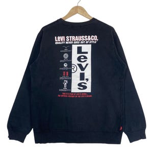 May include: Black Levi's sweatshirt with a white and red graphic on the back. The graphic includes the Levi's logo and the text "LEVI STRAUSS & CO. QUALITY NEVER GOES OUT OF STYLE." The sweatshirt has long sleeves and a crew neck.