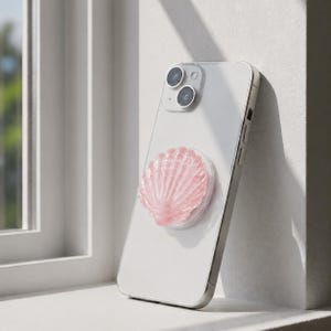 Op de afbeelding: Een lichtgekleurde smartphone met een doorschijnende achterkant en een dubbel camerasysteem, voorzien van een lichtroze, halfdoorzichtige, schelpvormige telefoongreep in het midden, met gedetailleerde ribbels en een glanzende afwerking.
