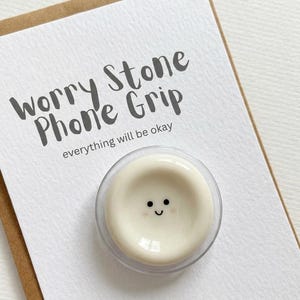 Soporte para teléfono con forma de piedra antiestrés y carita sonriente – Beige moteado