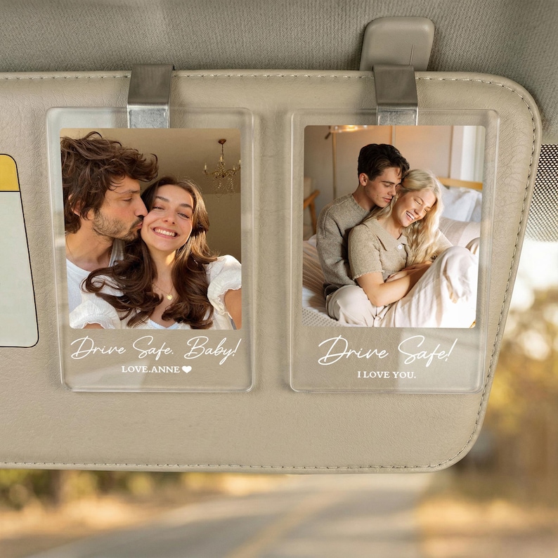 May include: Two rectangular clear acrylic car visor clips featuring custom photo prints of couples. The left clip displays the text Drive Safe. Baby! LOVE.ANNE and the right clip displays the text Drive Safe! I LOVE YOU. Both are attached to a beige visor.