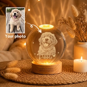 Könnte beinhalten: Eine leuchtende Kristallkugel mit einer detaillierten Gravur eines Hundegesichts, die auf einem Holzsockel ruht. Der Text "Pebble" und "LOVED ALWAYS MISSED FOREVER" sind in den Kristall geätzt. Ein Foto des Hundes befindet sich in der oberen linken Ecke.