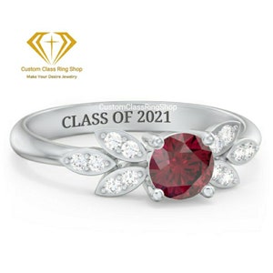 May include: A silver ring with a red gemstone and small white gemstones set in a leaf design. The ring is engraved with the text "CustomClassRingShop CLASS OF 2021".