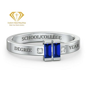 May include: A silver class ring with two blue rectangular gemstones and two small diamonds. The ring is engraved with the text "SCHOOL/COLLEGE", "DEGREE", and "YEAR".