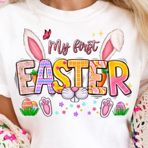May include: White t-shirt with a colorful graphic that says "My first Easter" with bunny ears and a cute bunny face.