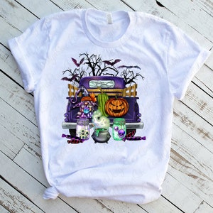 K&ouml;nnte beinhalten: Ein wei&szlig;es T-Shirt mit einem lila Pickup, der eine Hexe, einen K&uuml;rbis und einen Kessel transportiert. Der Truck ist mit Halloween-Dekorationen geschm&uuml;ckt, darunter Flederm&auml;use, Spinnweben und S&uuml;&szlig;igkeiten.