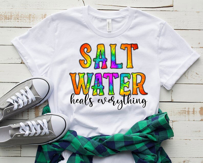 Puede incluir: Camiseta blanca con un dise&ntilde;o tie-dye que dice "Salt Water heals everything".