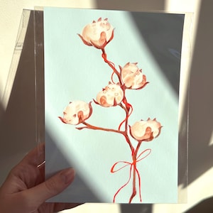 May include: A watercolor painting of a branch with five cotton balls, each with a small white cat sleeping inside. The branch is tied with a red ribbon.
