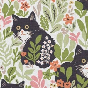 Peut inclure: Motif de tissu avec des chats noirs entourés de feuillages et de fleurs verts, oranges et roses. Les chats ont des marques blanches et des yeux jaunes. Le motif est sur fond crème.