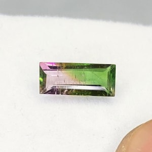 May include: A rectangular, faceted gemstone with a green, pink, and white color gradient.