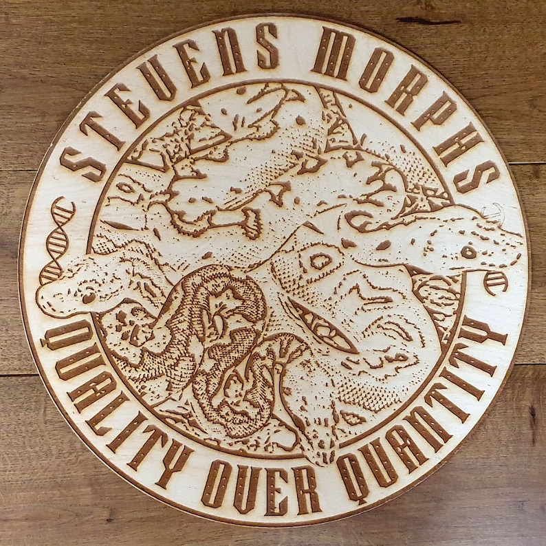 Peut inclure: Une enseigne ronde en bois avec une finition en bois brun. L'enseigne pr&eacute;sente un motif grav&eacute; au laser d&eacute;taill&eacute; de serpents entrelac&eacute;s avec le texte "Stevens Morphs" et "Quality Over Quantity".