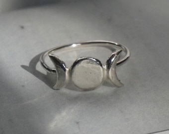 May include: A silver ring with a triple moon design. The ring is made of sterling silver and features three crescent moons.