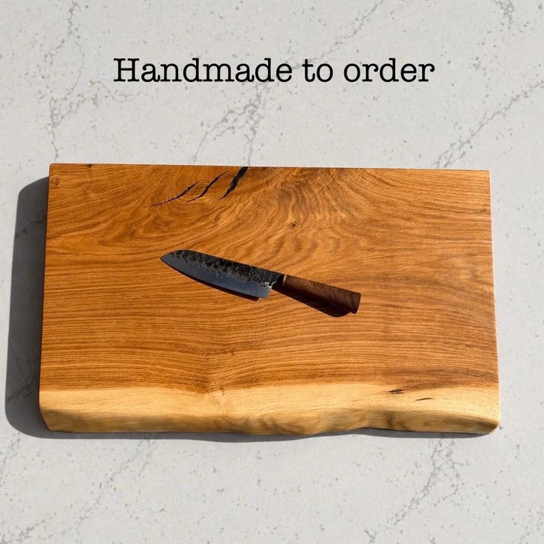 May include: A wooden chopping board with a live edge and a small knife. The board is light brown with darker wood grain patterns. The knife has a dark metal blade and a brown handle. Text on the image reads "Handmade to order."