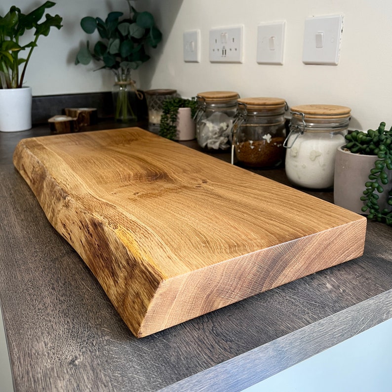 May include: A rectangular wooden chopping board with a natural edge. The board is made of light brown wood with visible grain and a smooth, finished surface. The board is approximately 46 cm long and 25 cm wide.