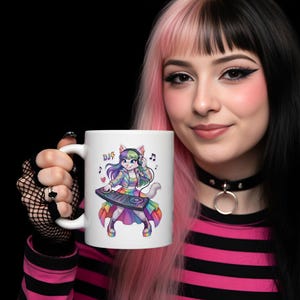 Op de afbeelding: Witte keramische mok met een cartoon kat DJ ontwerp. De kat draagt een koptelefoon en bedient een mengpaneel, met muzieknoten en het woord "DJ". Het ontwerp heeft een regenboogkleurenschema, waardoor het een levendig en opvallend item is.