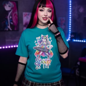 May include: Teal t-shirt featuring a colorful cartoon DJ cat with rainbow clothing and a DJ mixer. The shirt has the word "Spoop" in a stylized font. The design includes musical notes and a DJ symbol.
