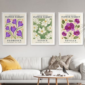 Puede incluir: Tres impresiones enmarcadas con un tema botánico. Cada impresión presenta una flor diferente y el nombre de una ciudad. Las impresiones se titulan "Mercado de flores" y las ciudades son Florencia, Venecia y Sevilla.