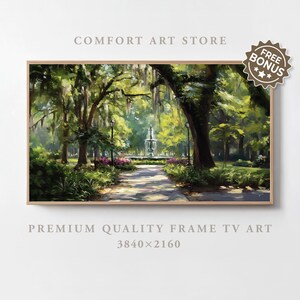 Op de afbeelding: Een ingelijst landschapsschilderij van een parkscène met een fontein, bomen en een pad. Het kunstwerk heeft een natuurlijk kleurenpalet van groen, bruin en blauw. De tekst "COMFORT ART STORE" en "PREMIUM QUALITY FRAME TV ART" zijn zichtbaar.