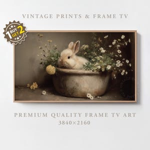 Op de afbeelding: Een ingelijste print met een vintage uitstraling, met een wit konijn tussen bloemen in een kom. De afbeelding heeft een gedempt kleurenschema. Tekst bevat "VINTAGE PRINTS & FRAME TV" en "PREMIUM QUALITY FRAME TV ART". De lijst is van hout.