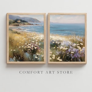 May include: Two framed landscape paintings depict a coastal scene with a beach, ocean, and wildflowers. The artwork features a color palette of blues, greens, and yellows, with a wooden frame. The text "COMFORT ART STORE" is printed below the paintings.