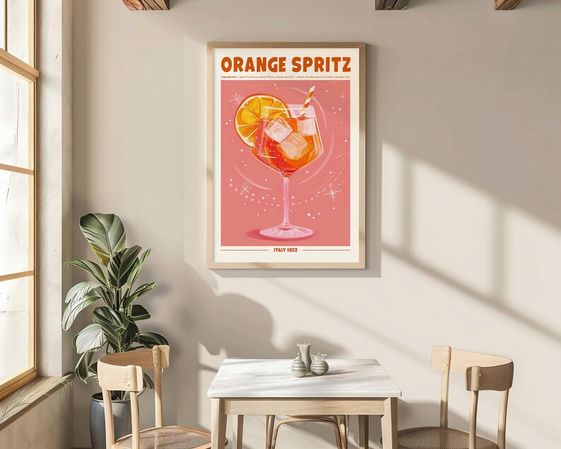 Puede incluir: Un p&oacute;ster enmarcado con las palabras "ORANGE SPRITZ" en la parte superior. El p&oacute;ster presenta una ilustraci&oacute;n estilizada de un c&oacute;ctel de naranja con cubitos de hielo y una pajita. El fondo es rosa claro con acentos en forma de estrella. El texto "ITALY 1952" est&aacute; en la parte inferior.